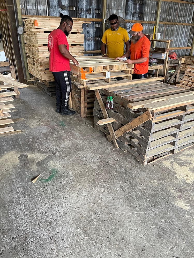 Three men measuring and building custom and standard pallets at Valley Pallet and Crating.