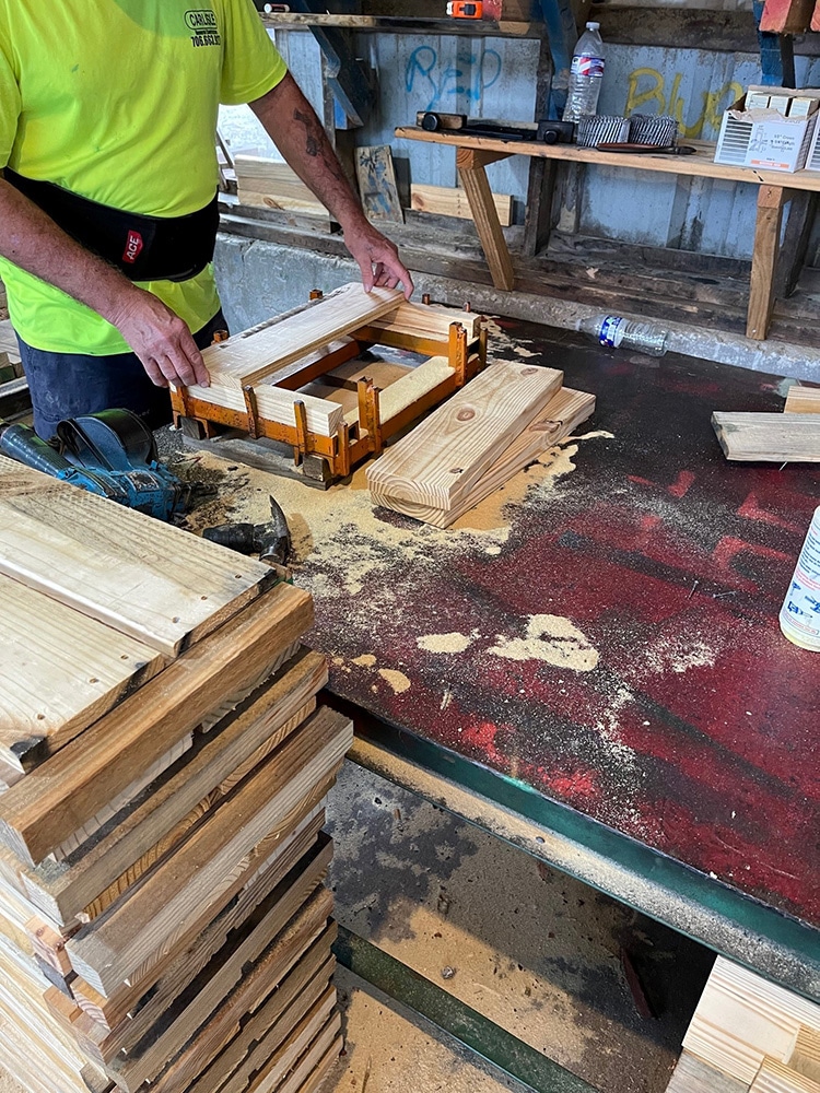Man measuring and cutting lumber for Valley Pallet and Crating customer.