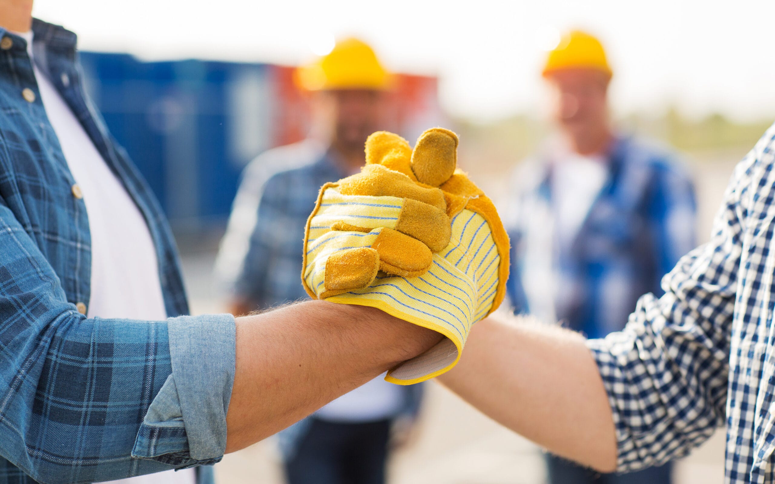 Partnership handshake between two workers wearing work gloves.