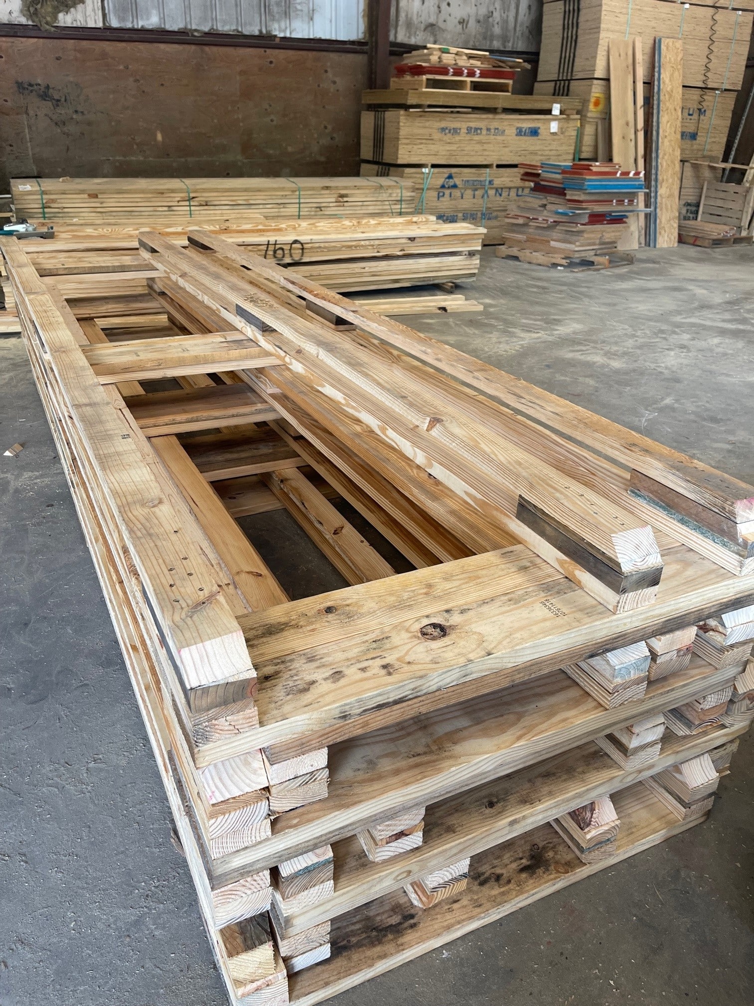 Stack of wooden skids on plant floor within Valley Pallet and Crating's manufacturing facility.
